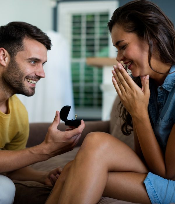Man offering a engagement ring to woman in the living room