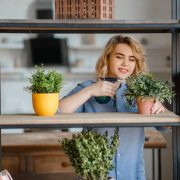 Young woman sprays home plants on the shelf