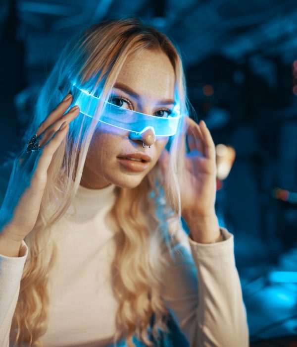Cute blonde in futuristic fashion style. Neon glasses for a young woman.