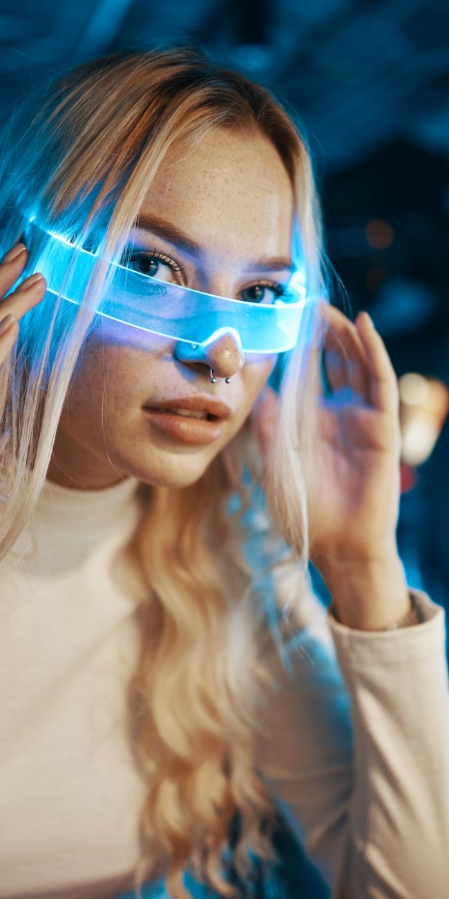 Cute blonde in futuristic fashion style. Neon glasses for a young woman.