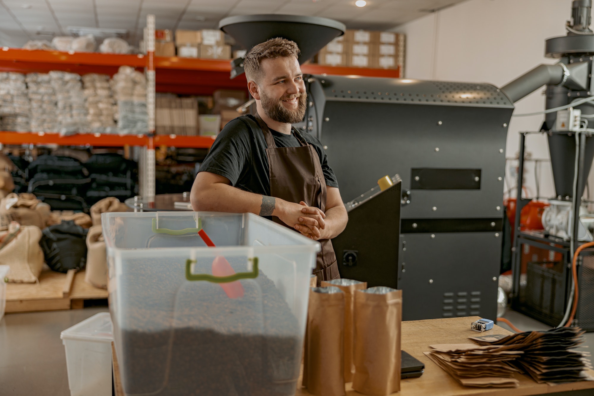 Portrait of smiling business owner on background of own small coffee factory looking away